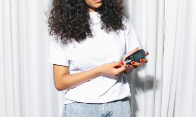 Eine junge Frau in weißem T-Shirt die gerade ihren Blutzucker misst